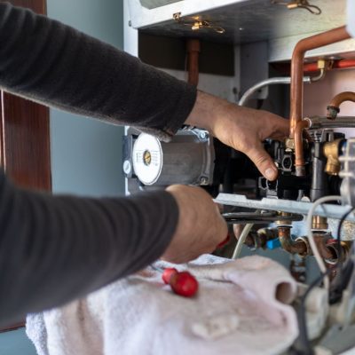 Technician Repairing Natural Gas Combi Boiler At Home