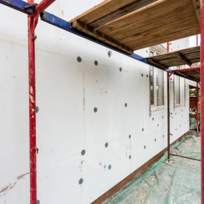 Modern repair and reconstruction of the house. Insulation of the house with polystyrene foam, plastering, applying plaster and painting facade walls using scaffolding when repairing the house. Construction or renovation.