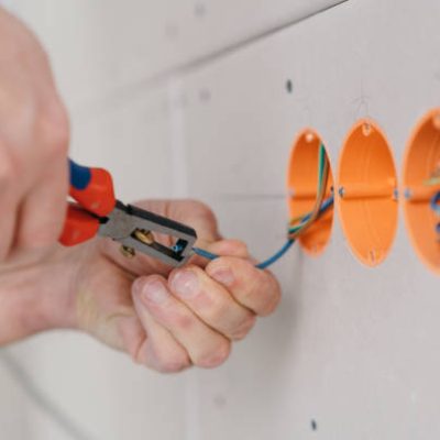 Handyman stripping an electric wire in a socket to make a connection in a close up on his hands